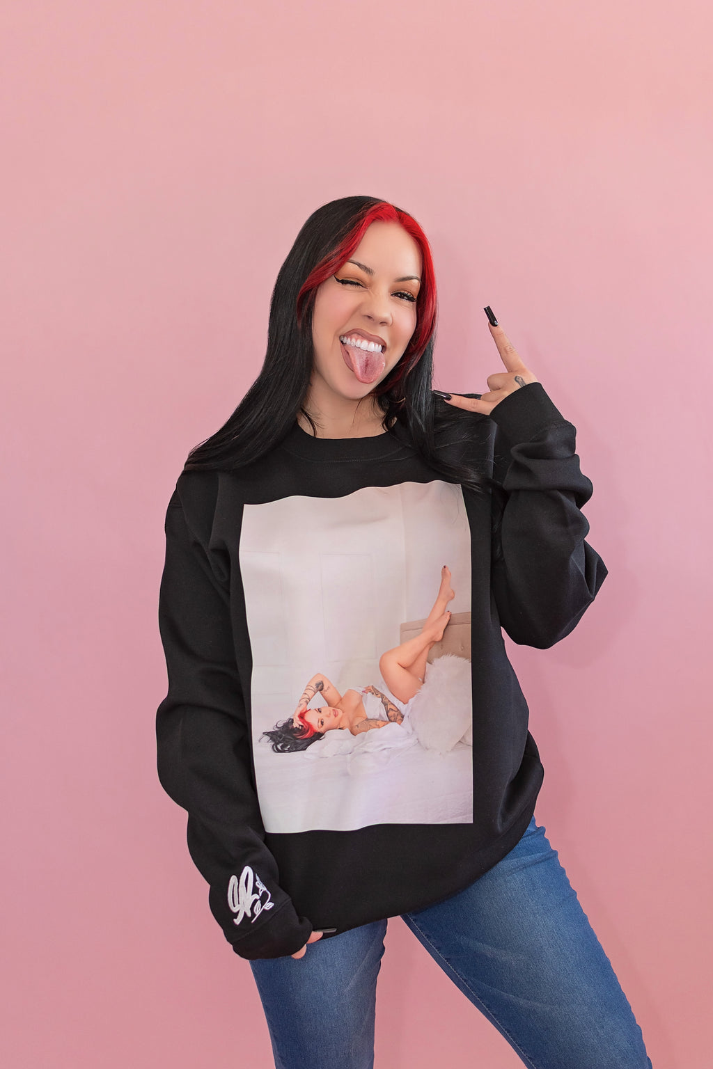 Person wearing a black sweatshirt with a graphic design on a pink background